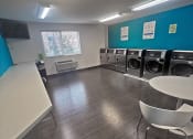 Thumbnail 7 of 11 - a laundry room with a row of washing machines and a table and chairs