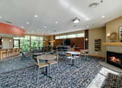 Thumbnail 23 of 32 - Community room with a variety of seating and tables and a large window wall