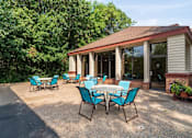 Thumbnail 25 of 32 - Outdoor patio with blue chairs and round tables in front of the indoor pool building