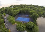 Thumbnail 30 of 32 - Aerial view of a blue basketball and tennis court surrouned by trees