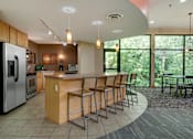 Thumbnail 21 of 32 - Community room with bar seating, a kitchen, and large windows