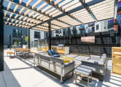 Thumbnail 13 of 44 - Outdoor community space with grills, sofas, and TV
