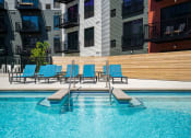 Thumbnail 15 of 44 - Pool and pool seating with apartment units' balconies in the background