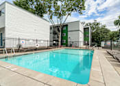 Thumbnail 2 of 20 - A swimming pool in front of a building with a green door.