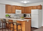 Thumbnail 5 of 32 - A kitchen with a white refrigerator and wooden cabinets.