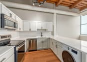 Thumbnail 12 of 22 - A modern kitchen with white cabinets and stainless steel appliances.