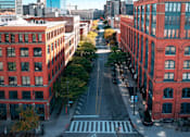 Thumbnail 4 of 22 - A street view of a city with red buildings on either side.
