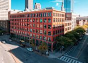 Thumbnail 3 of 22 - A red brick building with green windows sits on a street corner.