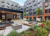 Thumbnail 4 of 76 - A modern outdoor seating area with a fireplace and a variety of plants.