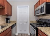 Thumbnail 9 of 20 - a kitchen with granite counter tops and a white door at Sawgrass Apartments, South Carolina, 29412