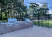 Thumbnail 5 of 20 - a patio with two bbq pits and a black fence at Sawgrass Apartments, Charleston, SC
