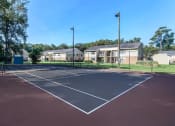 Thumbnail 6 of 20 - an empty tennis court with apartments in the background at Sawgrass Apartments, Charleston, 29412