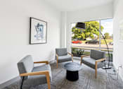 Thumbnail 9 of 26 - A living room with a grey sofa, a grey armchair, a black coffee table and a picture on the wall at The Point Apartments on 38th, Norfolk, Virginia