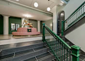 Thumbnail 30 of 43 - A staircase with a green railing and a pink couch in the background at The Carousel Apartments, Richmond, 23220