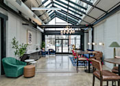 Thumbnail 25 of 43 - A modern cafe with a glass ceiling and wooden furniture at The Carousel Apartments, Richmond, Virginia