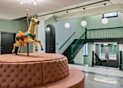 Thumbnail 31 of 43 - A carousel horse is on a round, tufted table in a room with a staircase at The Carousel Apartments, Richmond