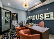Thumbnail 20 of 43 - A room with a desk, chairs, and a sign at The Carousel Apartments, Richmond, Virginia