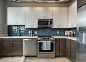 Thumbnail 46 of 51 - A modern kitchen with stainless steel appliances and white cabinets at The Carousel Apartments, Richmond, Virginia