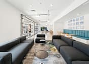 Thumbnail 5 of 26 - A modern living room with black leather sofas and a glass wall at The Point Apartments on 38th, Norfolk, Virginia