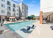 Thumbnail 3 of 26 - A pool with a slide and sun loungers in front of apartment buildings at The Point Apartments on 38th, Norfolk, Virginia