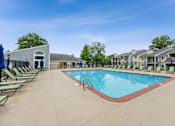 Thumbnail 8 of 25 - A large outdoor swimming pool surrounded by sun loungers and a building in the background at Chinoe Creek Apartments, Kentucky