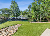 Thumbnail 15 of 26 - A green lawn with a stone pathway and a bench at Proximity Apartments, South Carolina, 29414