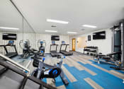 Thumbnail 8 of 19 - a gym with cardio equipment and a tv on the wall at Chapel View Apartments in Chapel Hill, NC