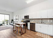Thumbnail 10 of 26 - a kitchen with white cabinetry and a wooden island with three stools  at The Point on 38th, Norfolk, VA