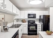 Thumbnail 18 of 37 - A modern kitchen with white cabinets and black appliances.at Chapel View, Chapel Hill, NC
