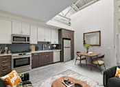 Thumbnail 32 of 43 - A modern kitchen with a dining table and chairs at The Carousel Apartments, Richmond, VA