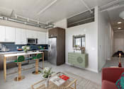 Thumbnail 39 of 43 - A modern kitchen with a red chair and a wooden table at The Carousel Apartments, Richmond, 23220