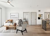 Thumbnail 22 of 26 - A modern living room with a white sofa, a wooden coffee table, and a black chair at The Point Apartments on 38th, Norfolk, Virginia