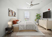 Thumbnail 21 of 25 - A bedroom with a bed, a ceiling fan, and a television at Circ Apartments, Virginia