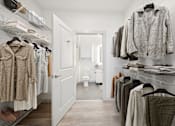 Thumbnail 22 of 25 - A walk in closet with clothes hanging and a toilet in the background at Circ Apartments, Virginia