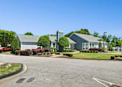 Thumbnail 16 of 21 - A building with a grey roof and a parking lot in front.