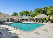 Thumbnail 9 of 21 - A swimming pool surrounded by a patio with chairs and a gazebo.