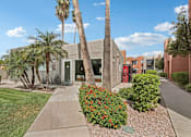 Thumbnail 17 of 26 - A building with a red door is surrounded by palm trees and bushes.