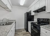 Thumbnail 4 of 26 - A kitchen with black appliances and white cabinets.