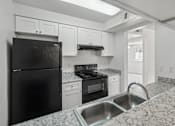 Thumbnail 2 of 26 - A black refrigerator is in a kitchen with granite countertops.