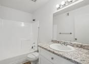 Thumbnail 13 of 26 - A white bathroom with a marble countertop and a toilet.