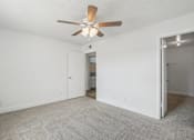 Thumbnail 6 of 26 - A room with a ceiling fan and carpeted floor.