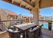 Thumbnail 22 of 29 - A patio with a table and chairs overlooking a pool. at Sundancer Apartments, Tolleson, AZ, 85353