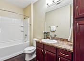 Thumbnail 21 of 22 - A white toilet sits next to a white bathtub in a bathroom at Overlook at Stone Oak Park Apartments, San Antonio