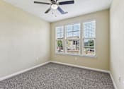 Thumbnail 19 of 22 - A room with a ceiling fan and a window showing a view of a house at Overlook at Stone Oak Park Apartments, San Antonio