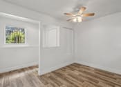 Thumbnail 12 of 26 - A room with a ceiling fan and wooden flooring.