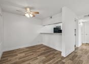 Thumbnail 3 of 26 - A room with a ceiling fan and wooden flooring.