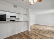 Thumbnail 8 of 26 - A kitchen with white cabinets and a black fridge.