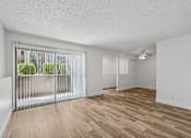 Thumbnail 5 of 26 - A room with a sliding glass door and wooden flooring.