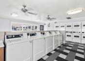 Thumbnail 13 of 16 - A laundry room with a checkered floor and a row of washers and dryers at North Mountain Apartments, Phoenix, Arizona