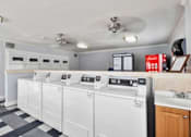 Thumbnail 15 of 16 - A row of washing machines in a laundry room. at North Mountain Apartments, Phoenix, AZ, 85020